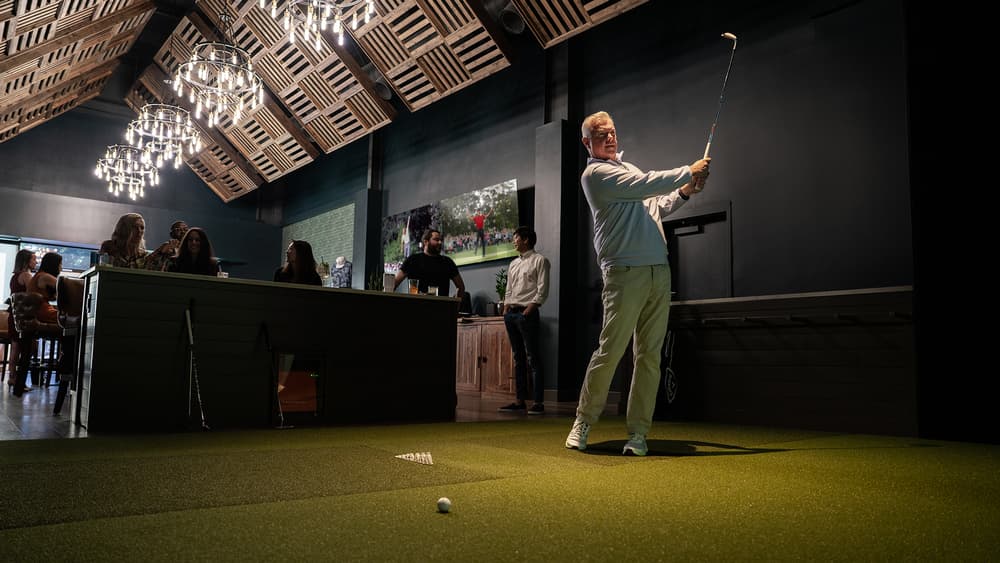 Member taking a swing in a Trackman bay at The Sanctuary